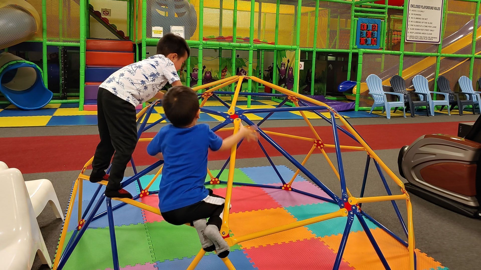 two young boys are playing on a climbing dome in a playground