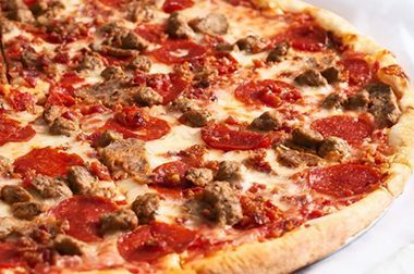 A pizza with pepperoni and sausage on it is sitting on a table.