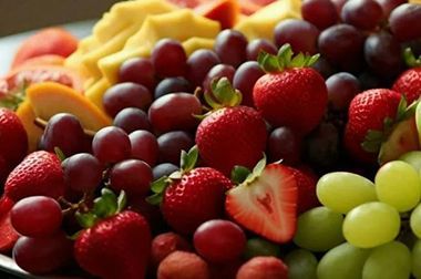 A plate of fruit including strawberries , grapes , and pineapples.