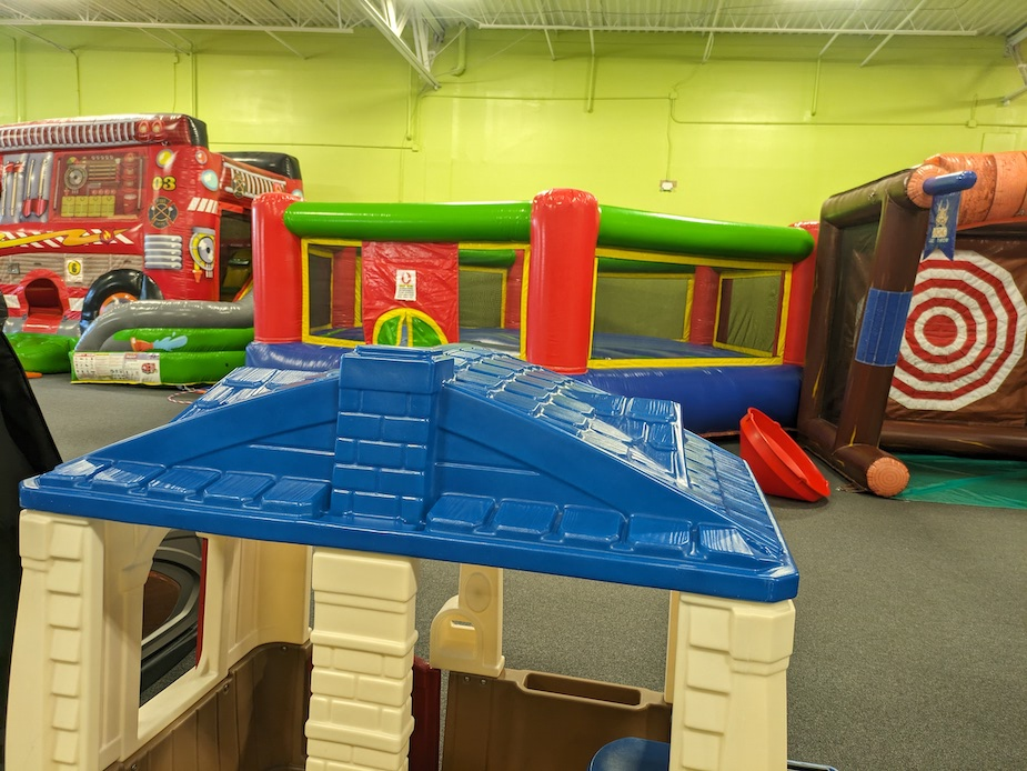 A playhouse is sitting in the middle of a room filled with bouncy houses.