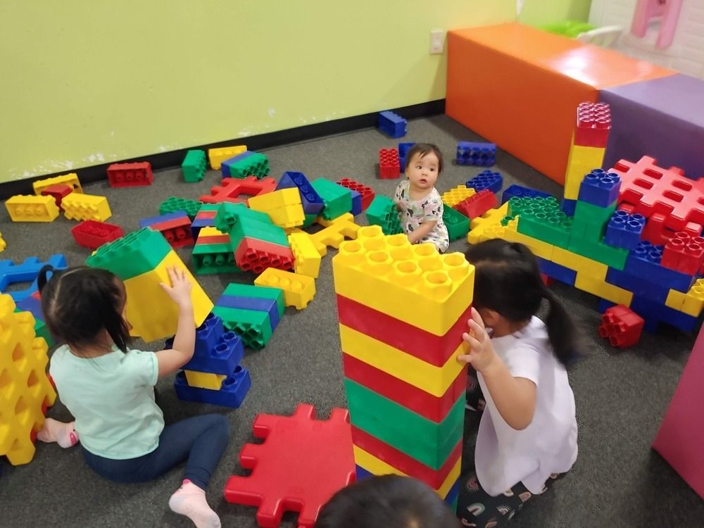 A group of children are playing with lego blocks on the floor.