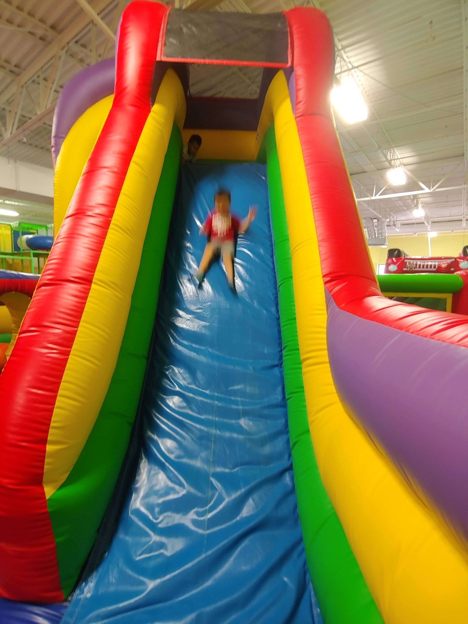 A child is riding down a colorful inflatable slide