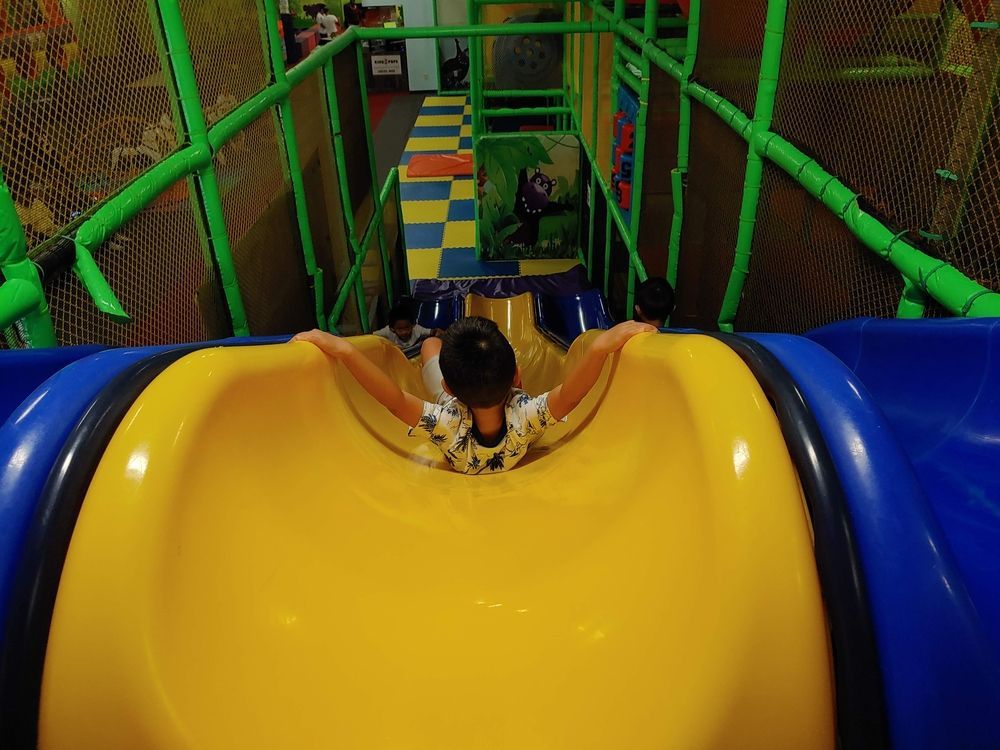 A child is sliding down a yellow slide in a playground.