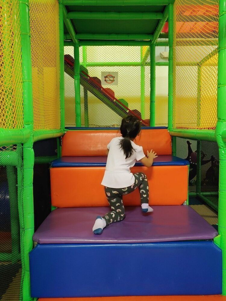 A little girl is climbing up a set of stairs in a playground.