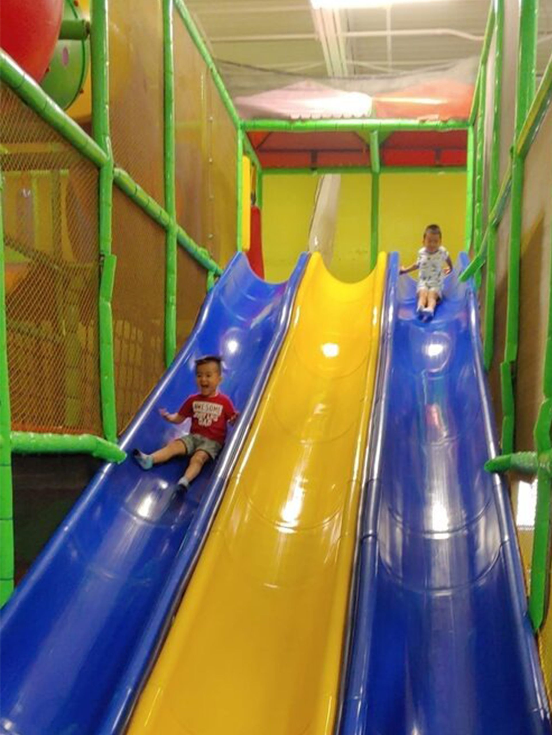 Two children are riding down a slide in a playground.