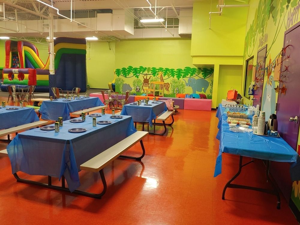 A room with tables and benches and a bouncy house in the background