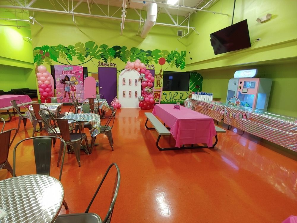A large room with tables and chairs and balloons on the walls.