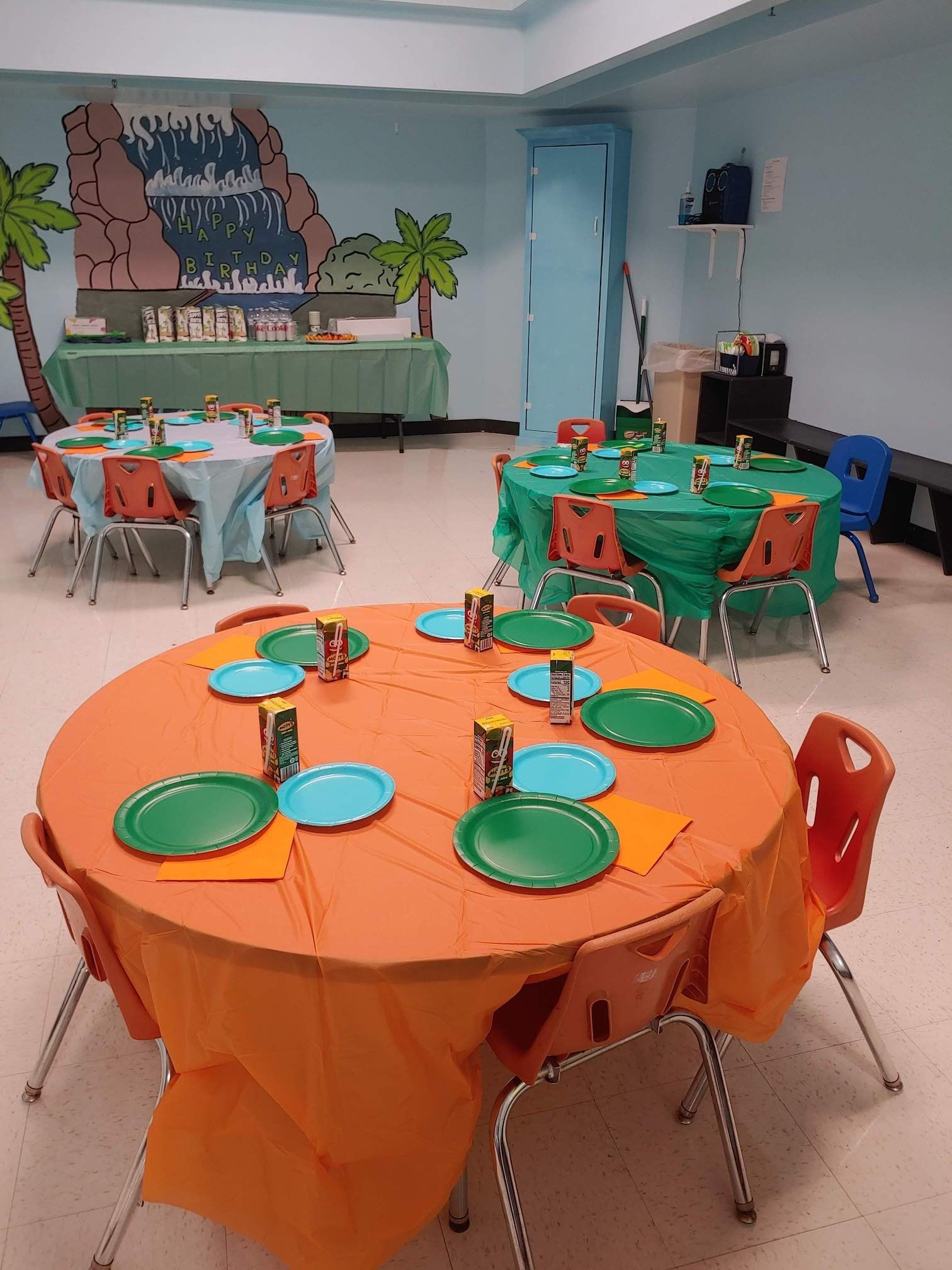 A room with tables and chairs set up for a birthday party.