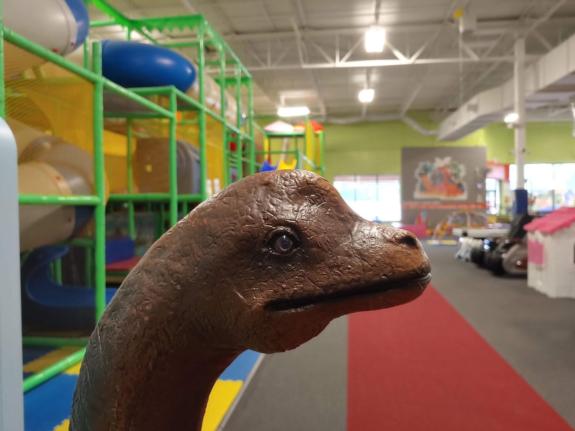 A statue of a dinosaur is standing in a playground