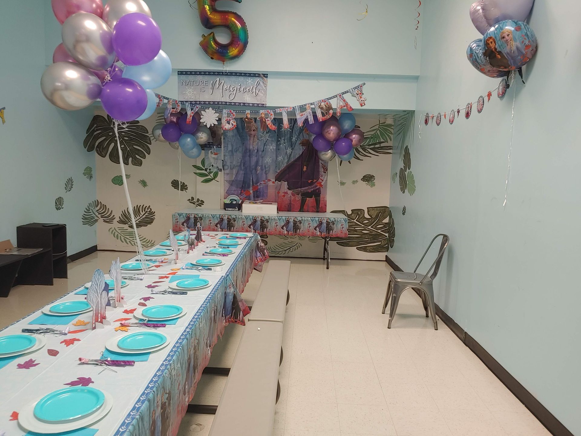 A room decorated for a birthday party with balloons and plates on the table.