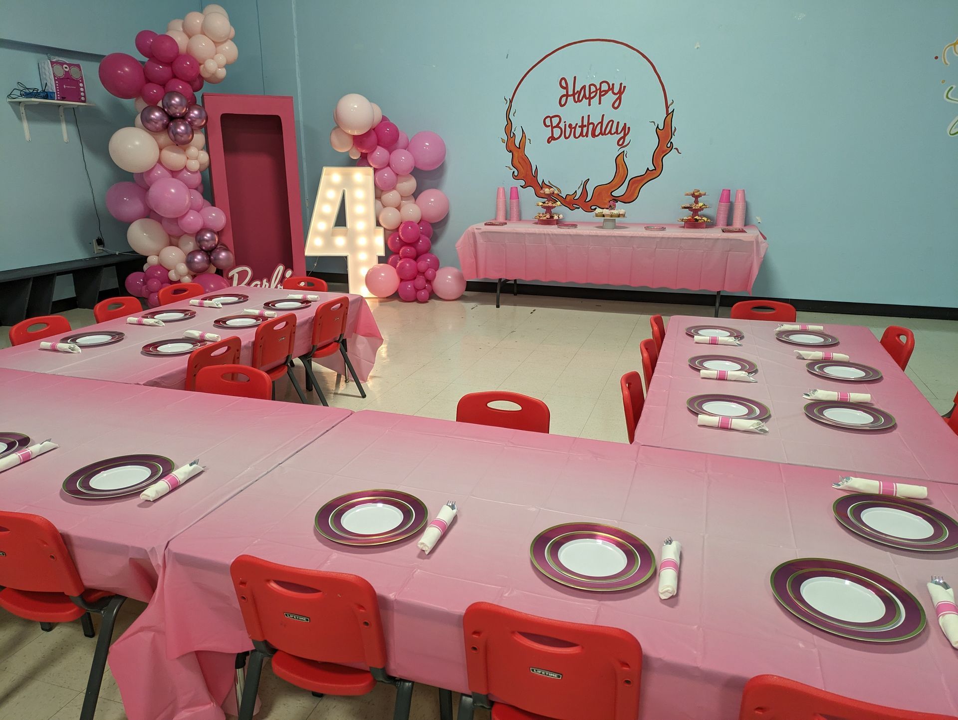 A room with tables and chairs set up for a birthday party.