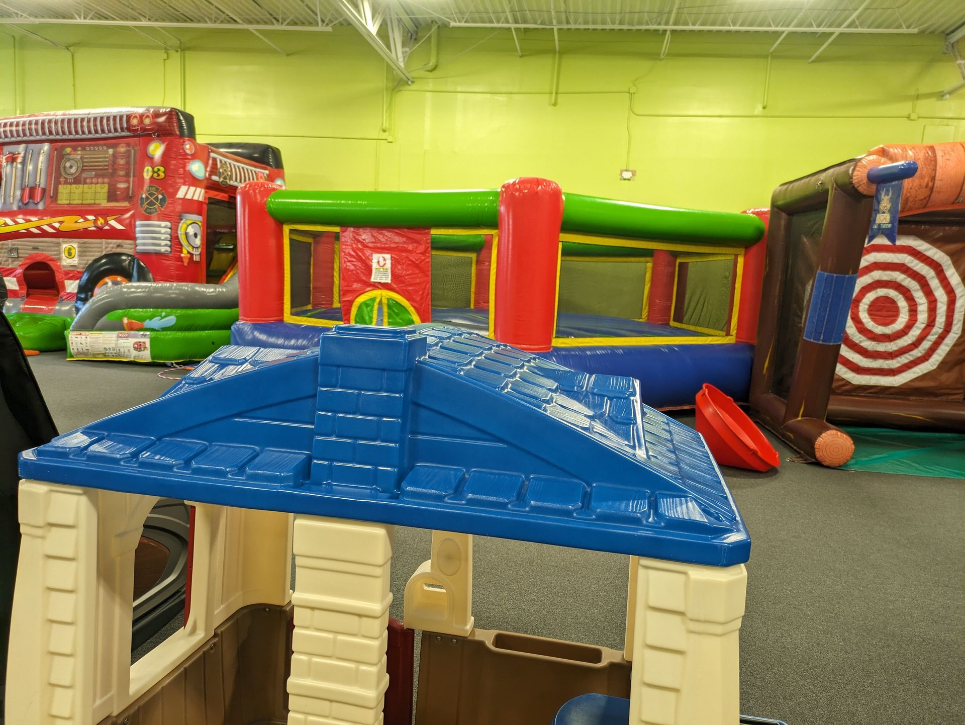 A playhouse is sitting in the middle of a room filled with bouncy houses.