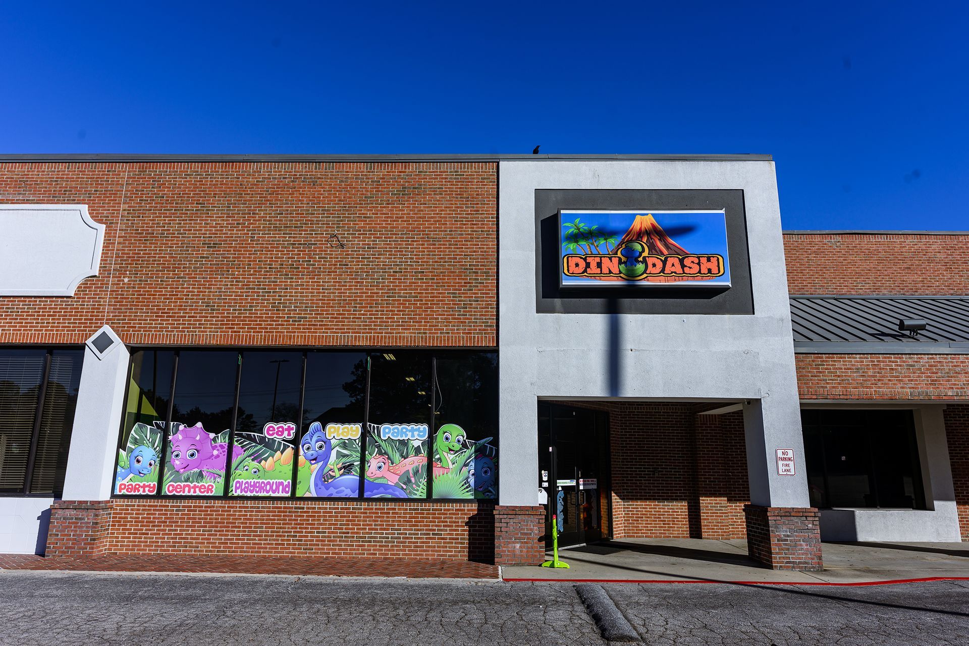 Storefront of  a toy store, brick and grey facade, with a brightly colored sign.