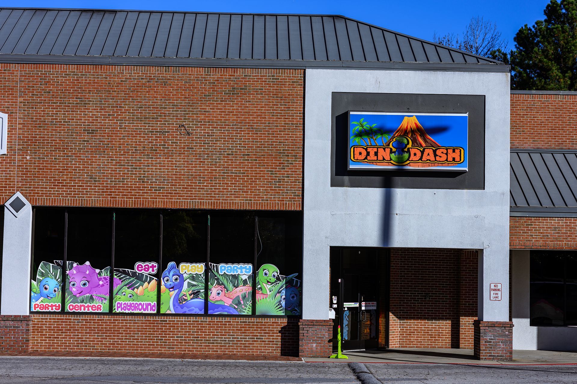 Storefront with sign, window displays of dinosaurs, and brick facade.