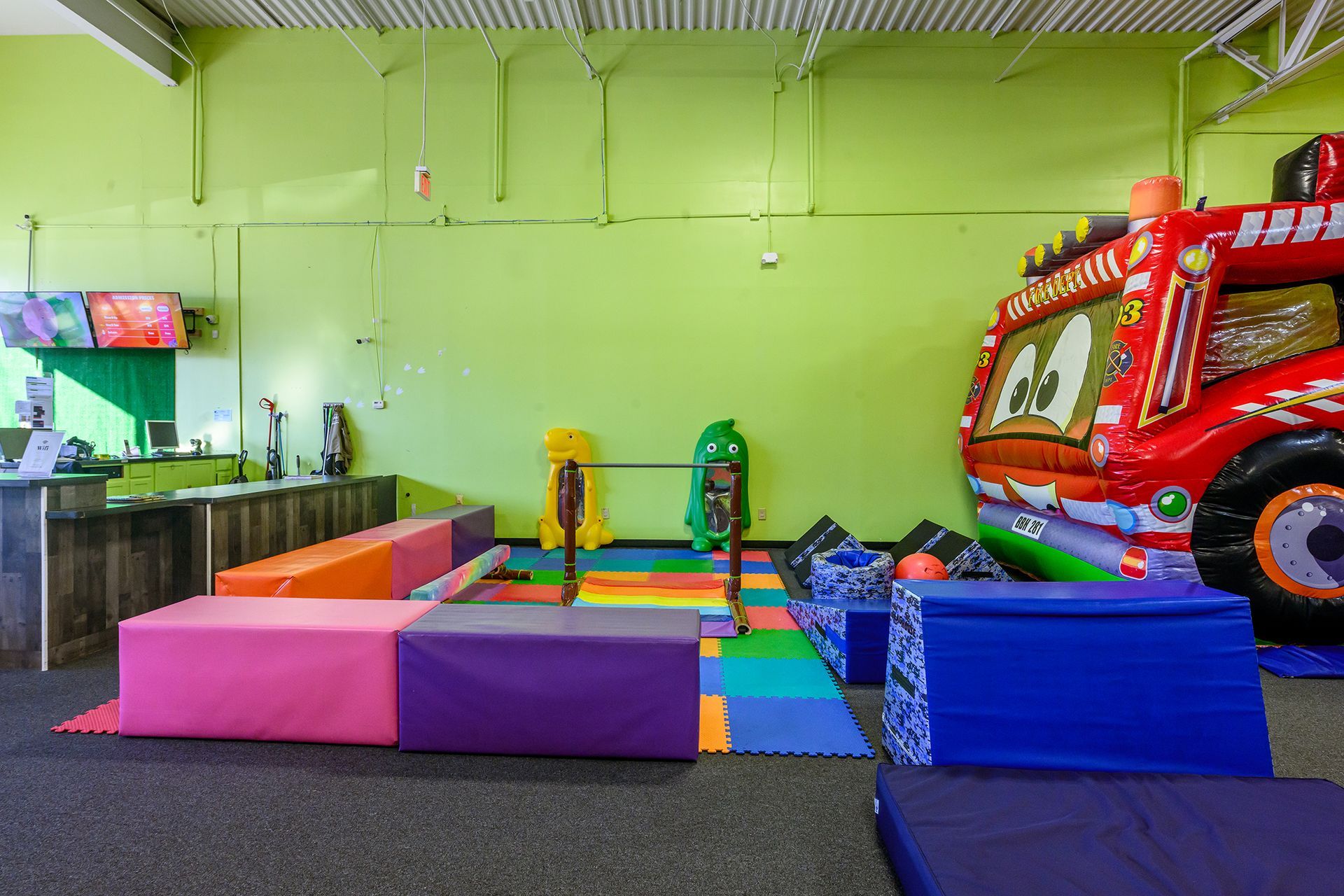 Playroom with foam blocks, gymnastics equipment, and a fire truck inflatable.