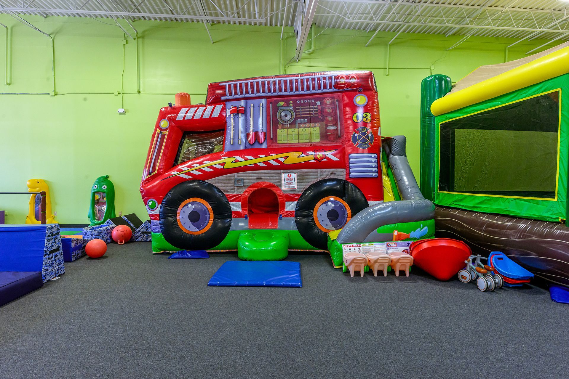 Indoor playground with a red inflatable fire truck and other play structures.
