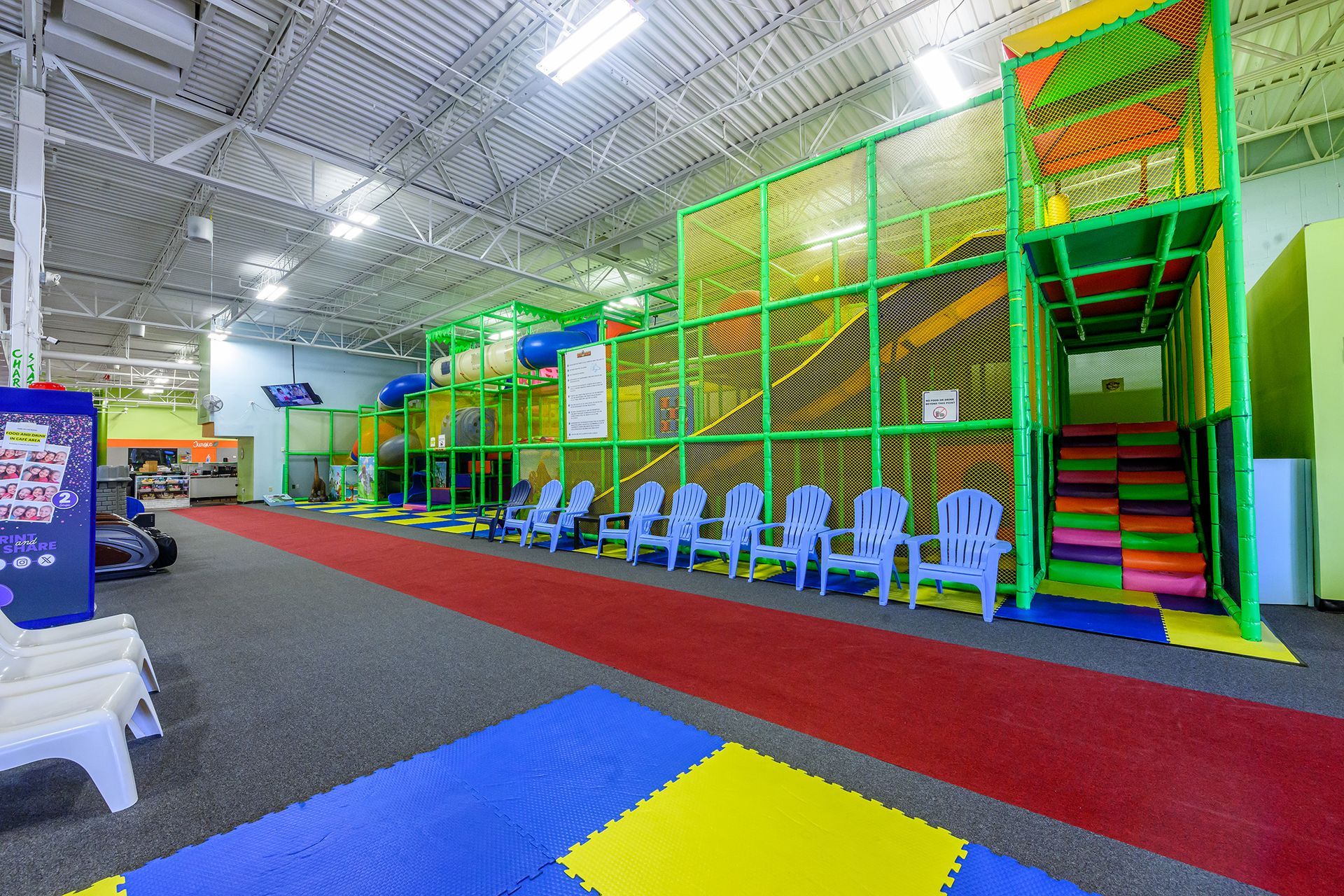 Indoor children's play area with climbing structures, seating, and colorful mats.