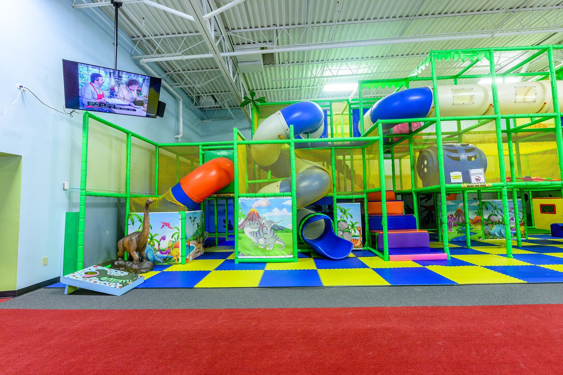 Indoor playground with colorful climbing structures, slides, and foam mats.