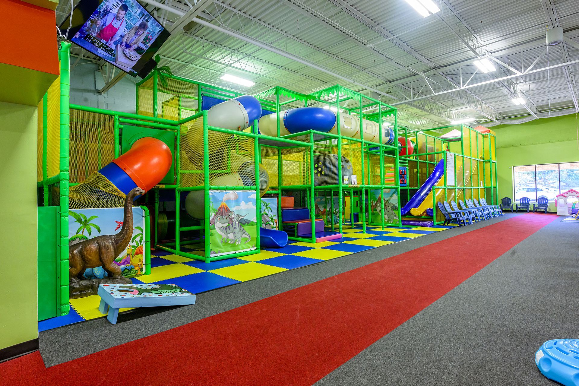 Indoor playground with colorful climbing structures, slides, and dinosaur decorations.