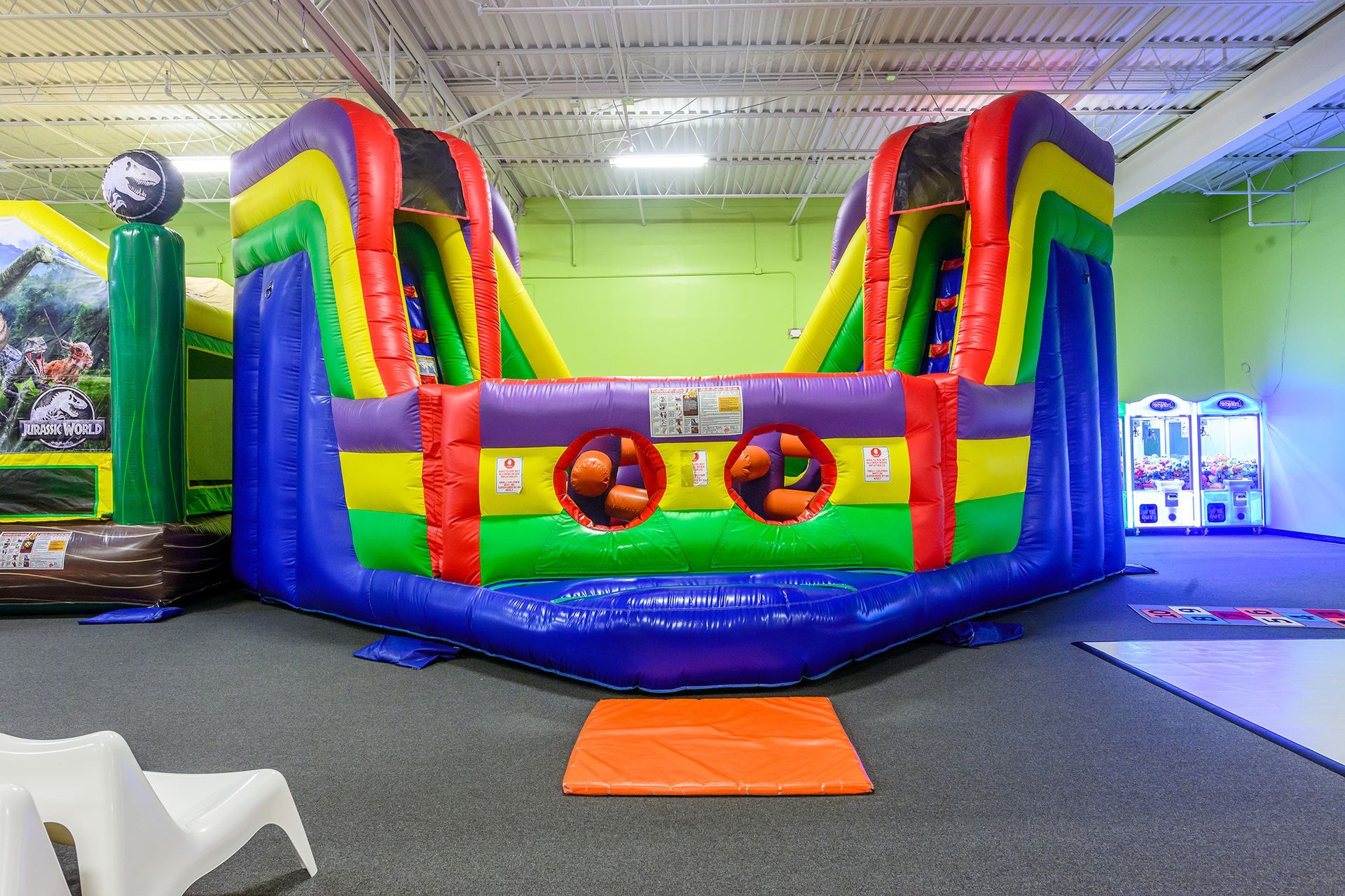 Colorful inflatable bounce house with two slides inside a play center.
