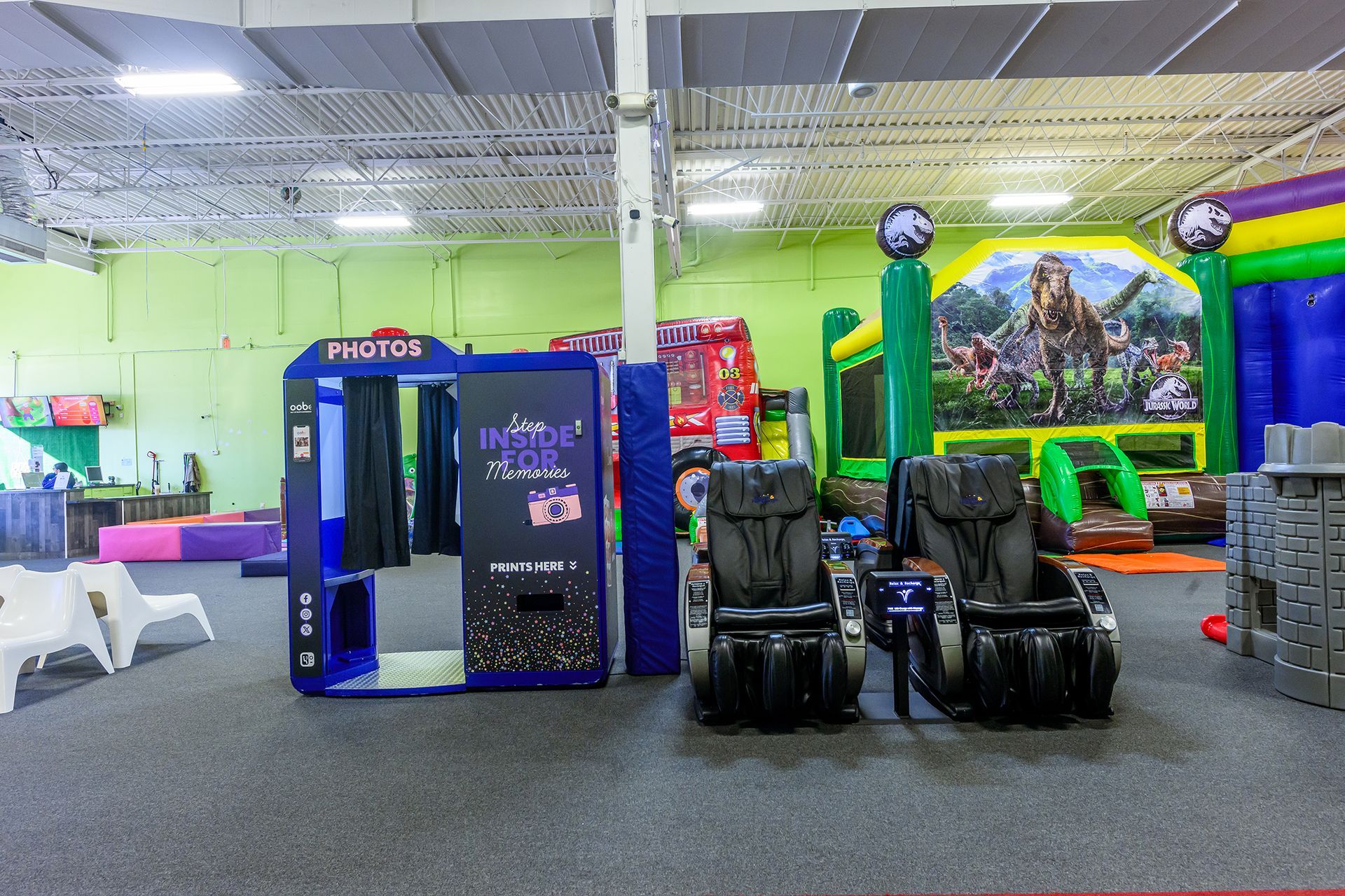 Playroom interior with photo booth, massage chairs, and inflatable bounce house.