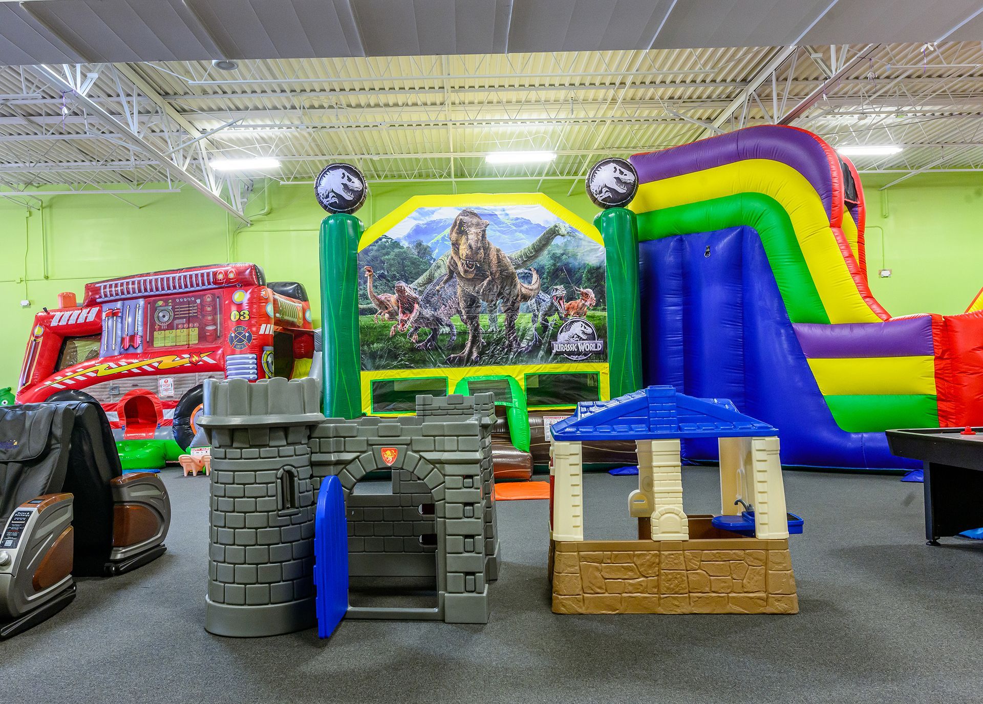 Indoor playground with inflatable slides, castle structure, and playhouse.