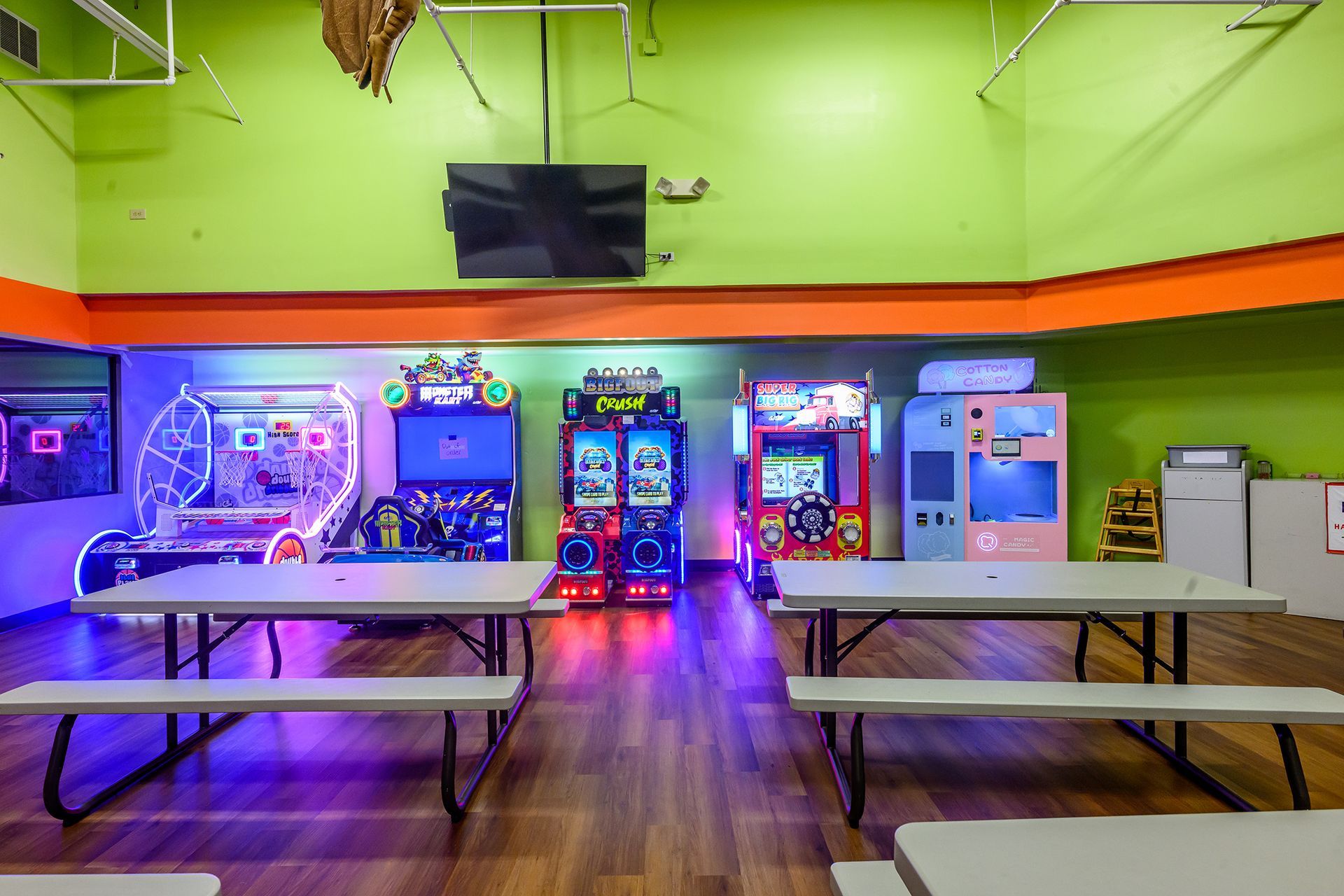 Arcade game room with tables, bright walls, and colorful arcade machines.