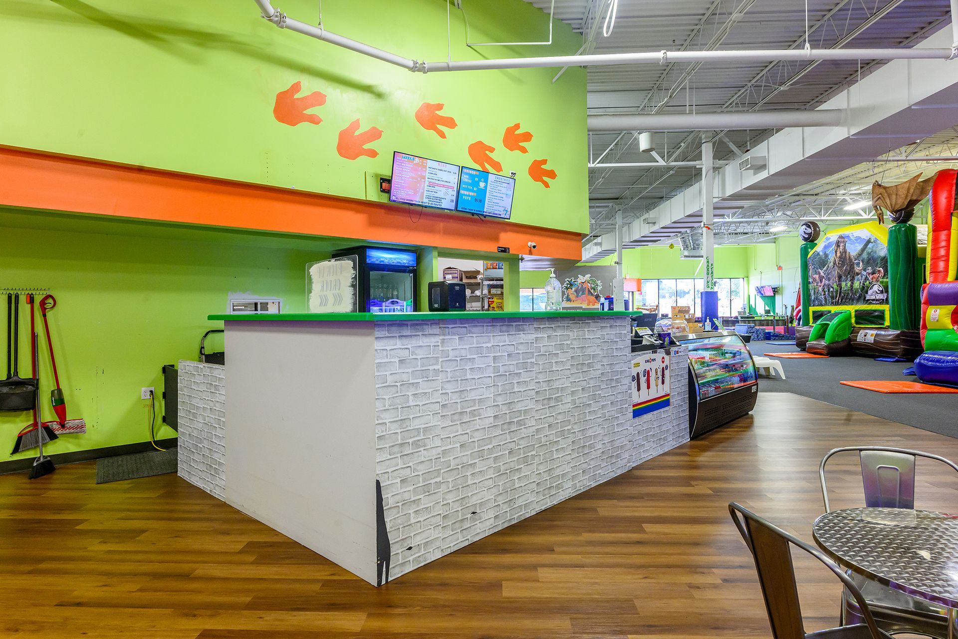 Reception area with a staff person, colorful walls, and play equipment in the background.