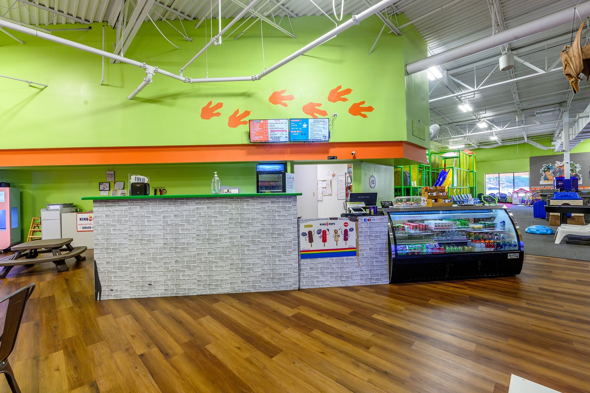 Indoor play area with front desk, snacks, and dinosaur footprint decorations.