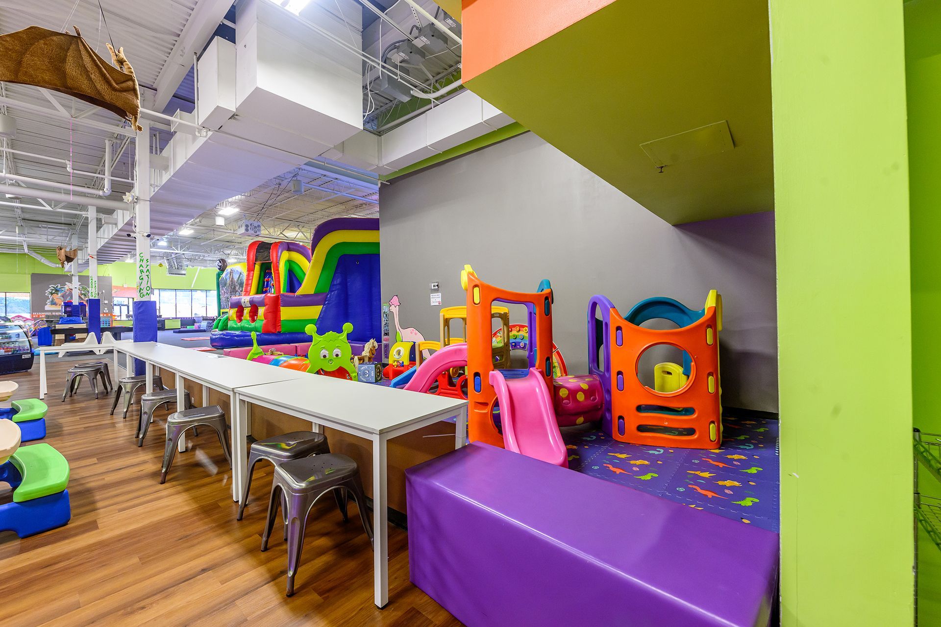 Indoor children's play area with tables, soft play structures, and inflatable slides.