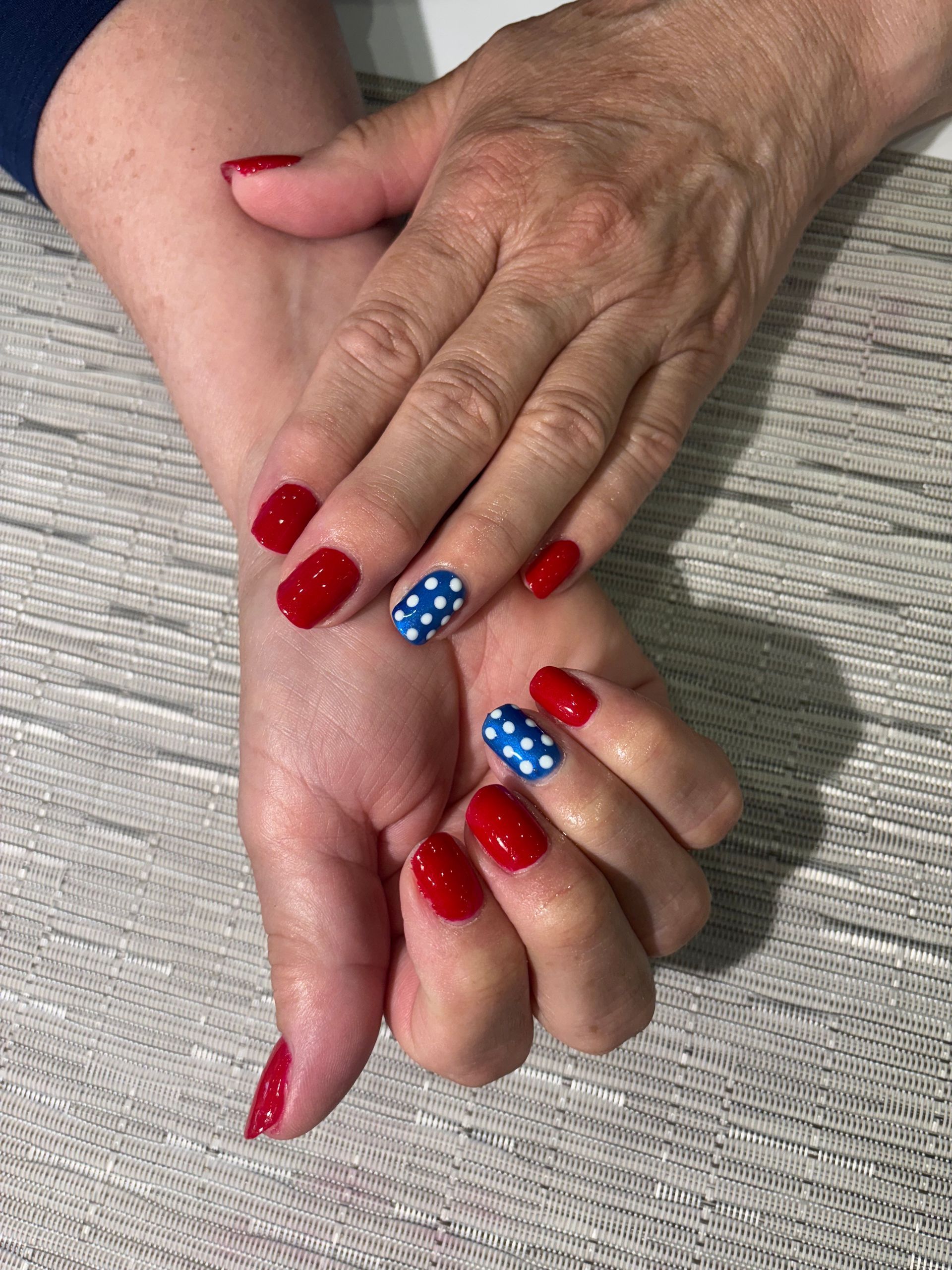 A woman's hands with red nails and blue and white polka dots