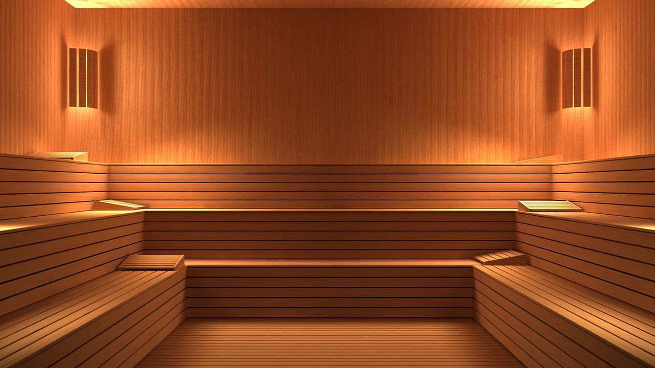 A wooden sauna with a lot of benches and lights on the walls.