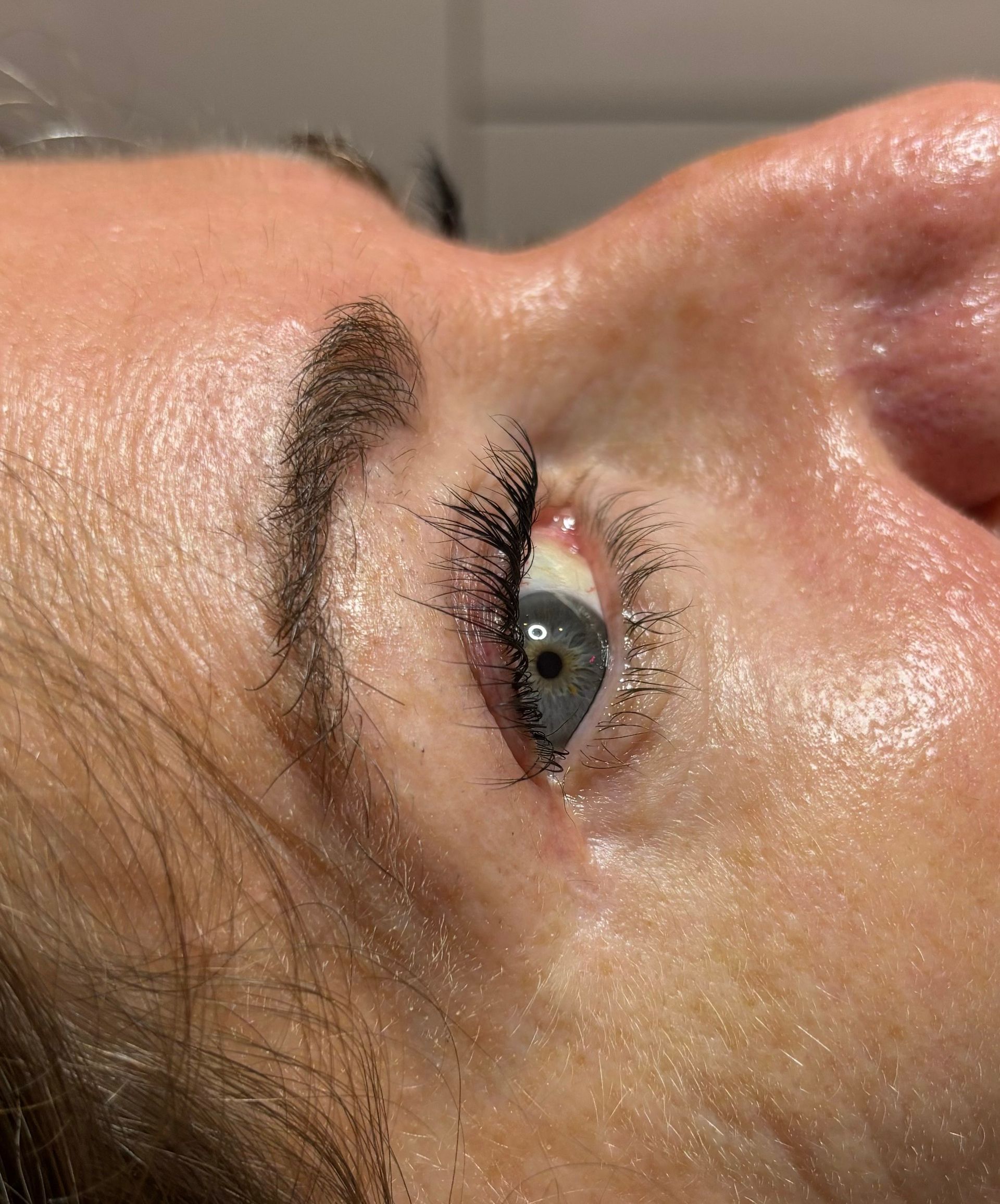 Close-up of a person's eye and eyebrow. Pale skin, blue eye with mascara, dark eyebrow.