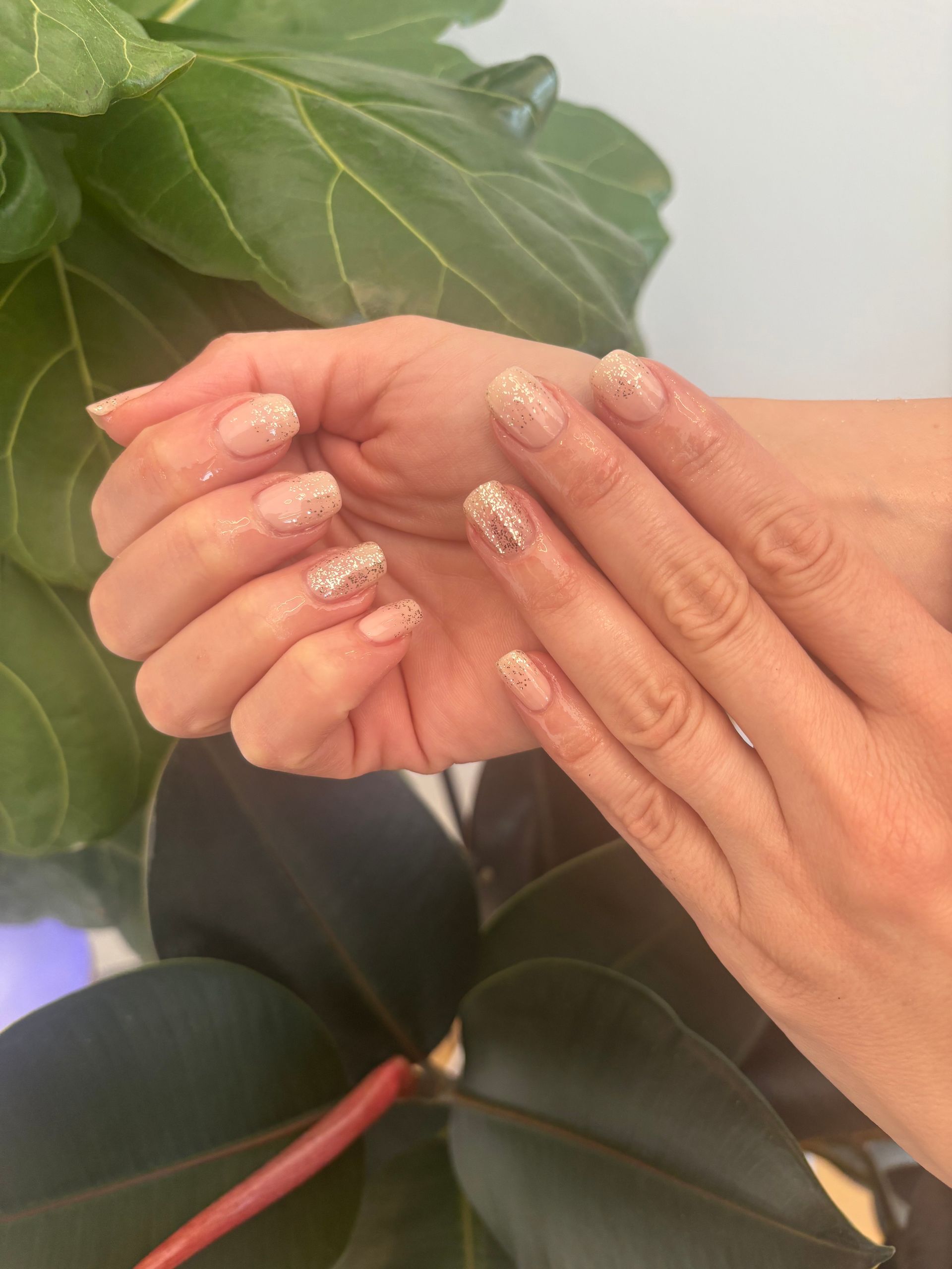 A close up of a person 's nails with a plant in the background.