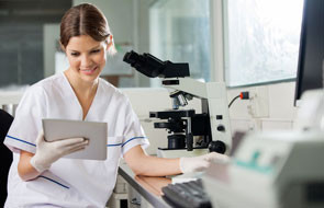 Happy young female scientist using digital tablet in lab
