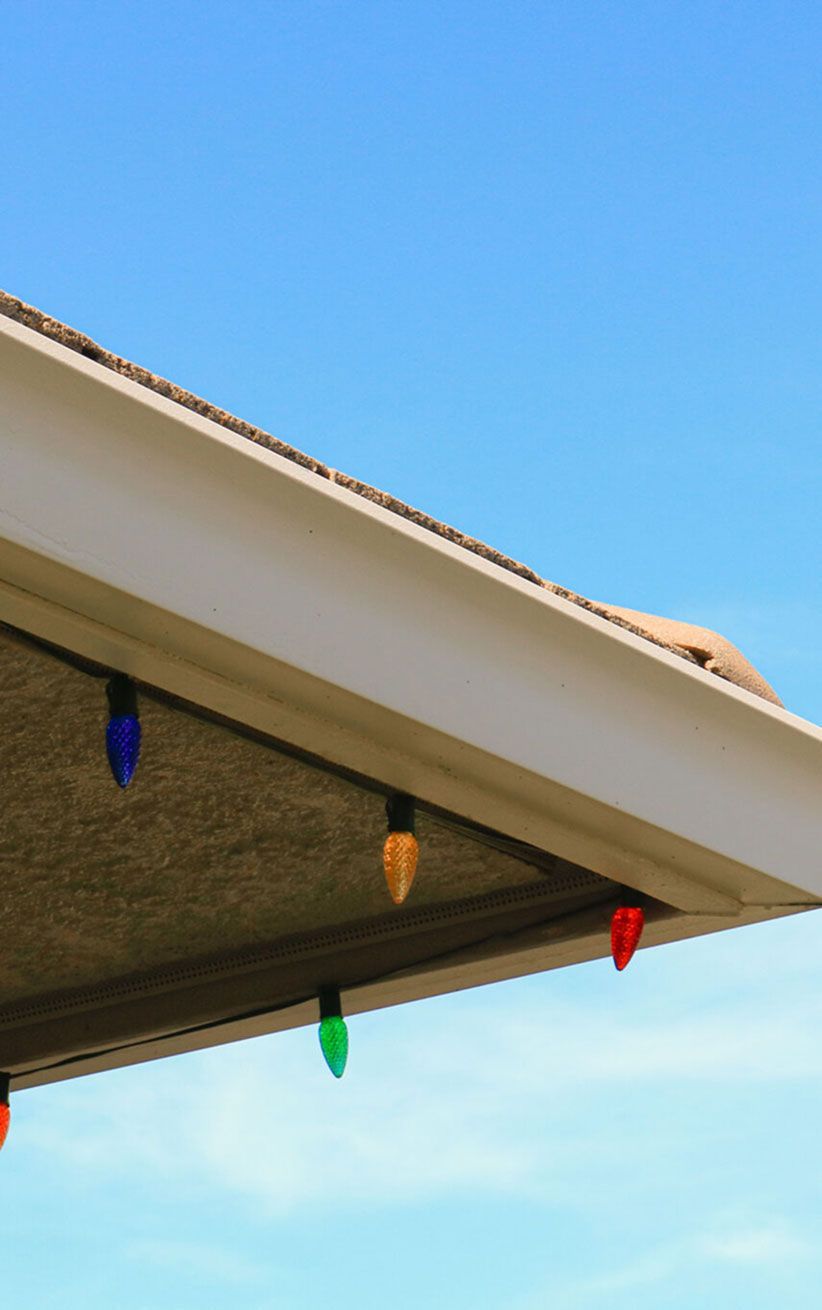 Colorful string lights hanging under a roof eave against a blue sky