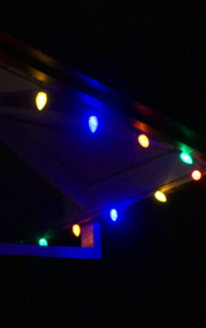 Colorful string lights glowing along a dark roofline at night