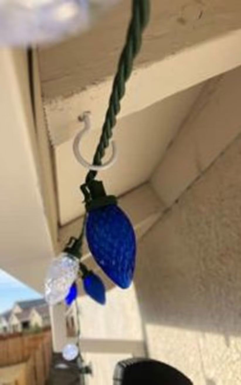 Blue decorative holiday lights hanging from a green cord under a porch roof.