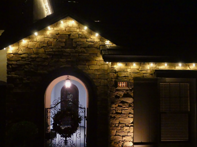 Stone house entrance lit by warm string lights at night