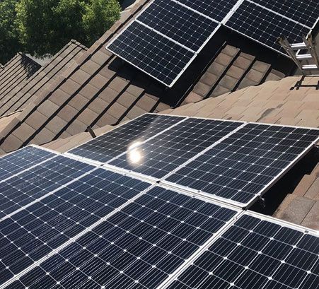 Solar panels mounted on a brown shingled roof in bright sunlight