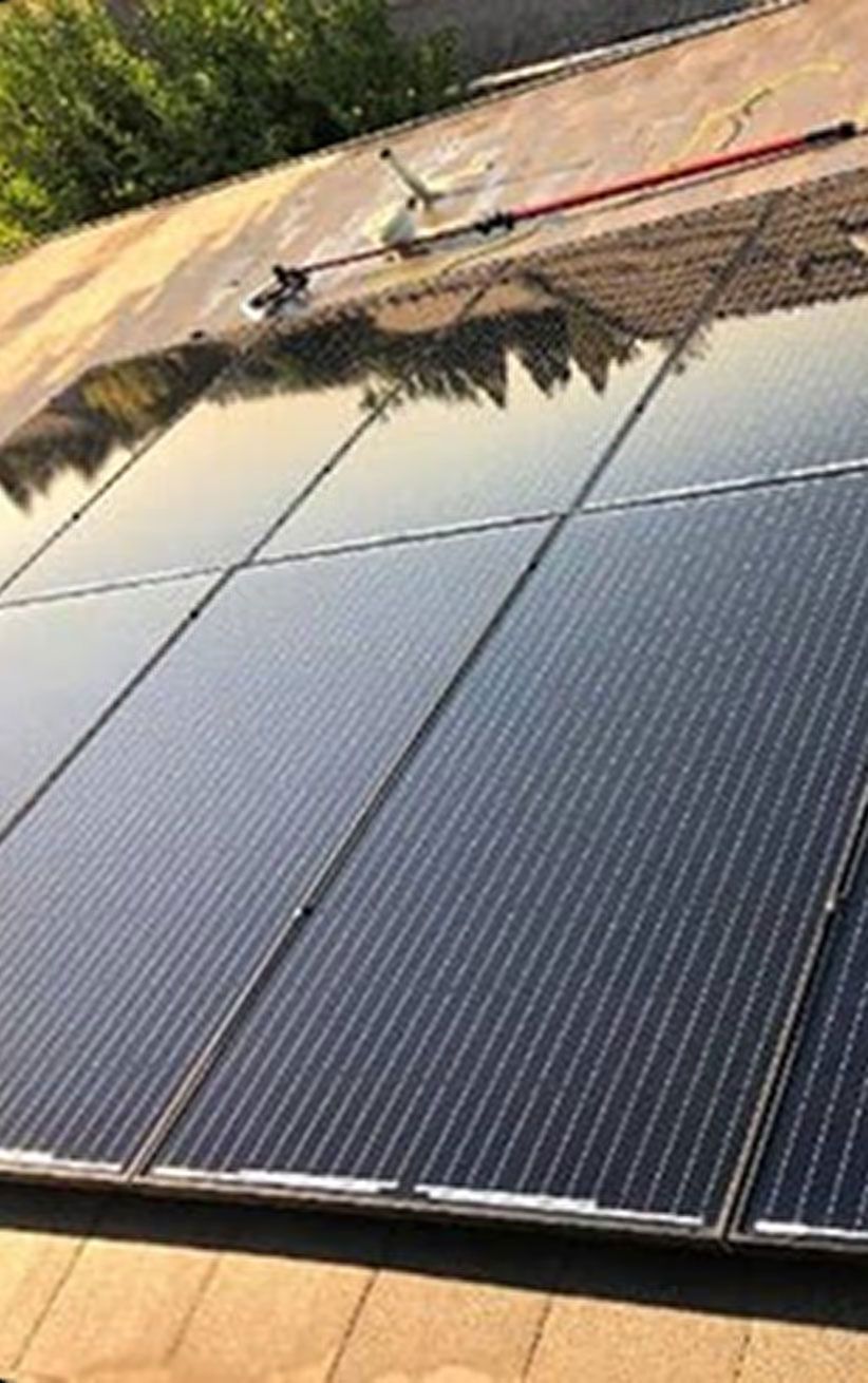 Rows of dark solar panels installed on a slanted rooftop under a blue sky.