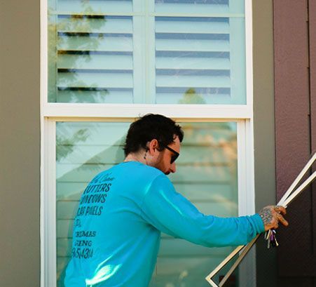 Worker in a turquoise shirt measuring a window frame with a tool outdoors
