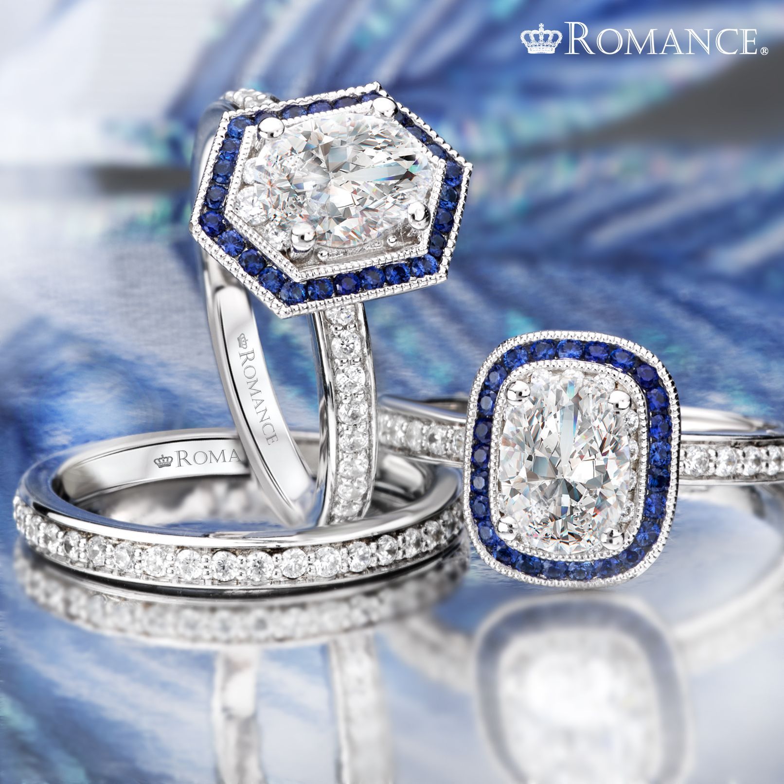 Three diamond rings with blue sapphire accents, on a reflective surface.