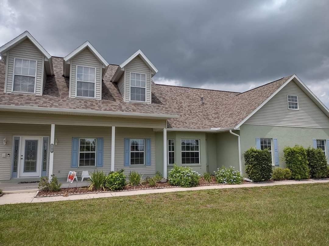 A large house with a lot of windows and a porch on a cloudy day.