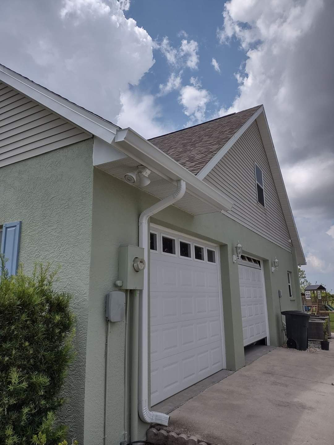 A house with two garage doors and a gutter on the side of it.