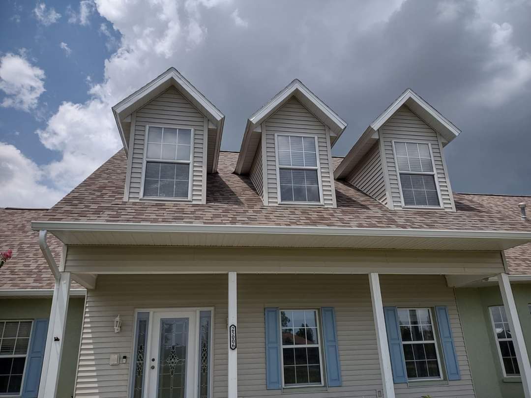 A house with three dormers and blue shutters on a cloudy day