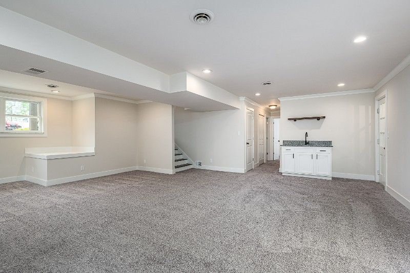 An empty basement with a staircase and a sink.