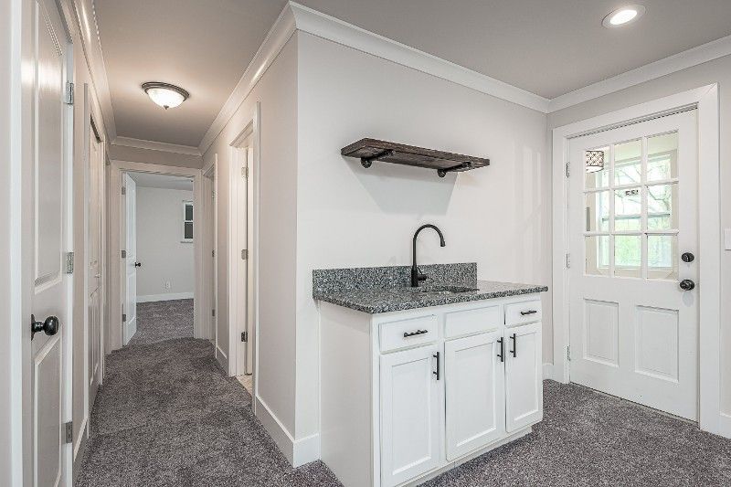 A hallway with a sink and cabinets in a house.