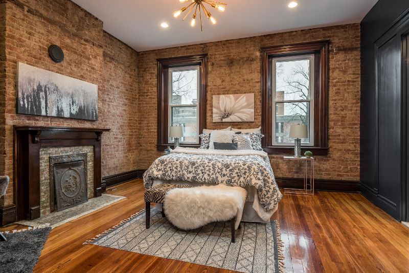 A bedroom with a bed , fireplace and brick walls.