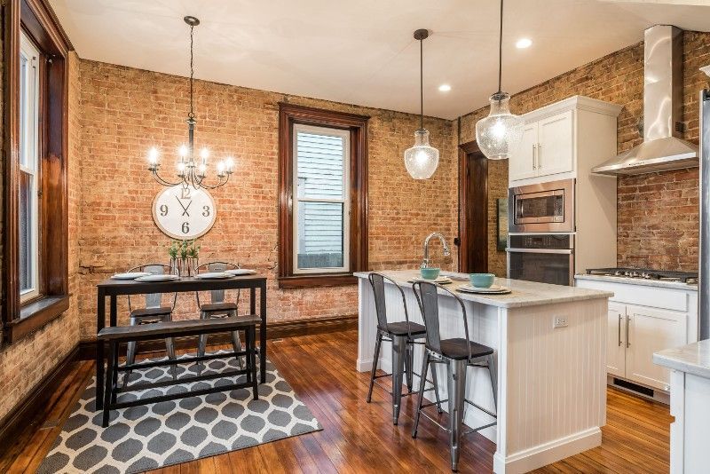 A kitchen with a table and chairs in it and a brick wall.